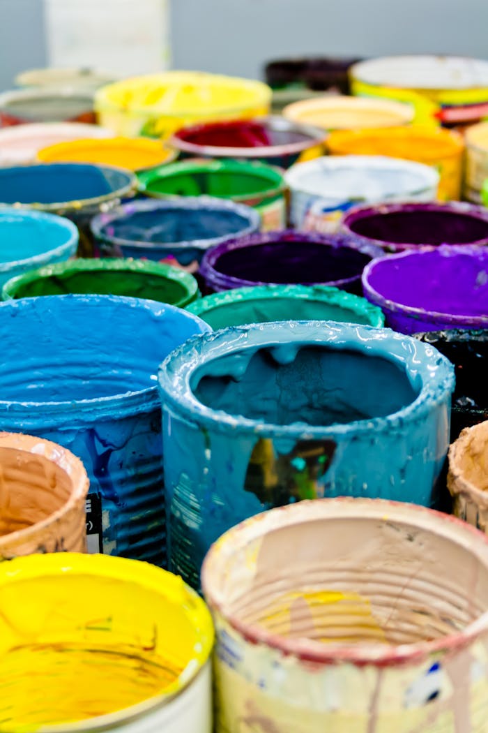 Home A vivid assortment of open paint cans displaying a spectrum of colors, ideal for artistic and design projects.